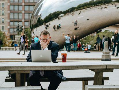 Un homme en tenue de ville travaillant sur son ordinateur assis à une table à Chicago© Tim Gouw via Pexels